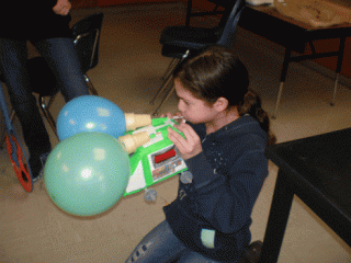 girl building car with balloons to make it go forward